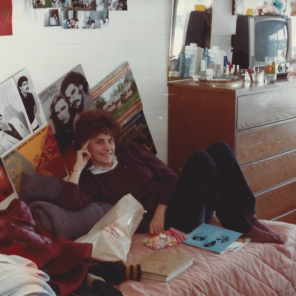 Scene from 1984: Girl in her college dorm room in front of her makeshift Hall & Oates shrine of album covers