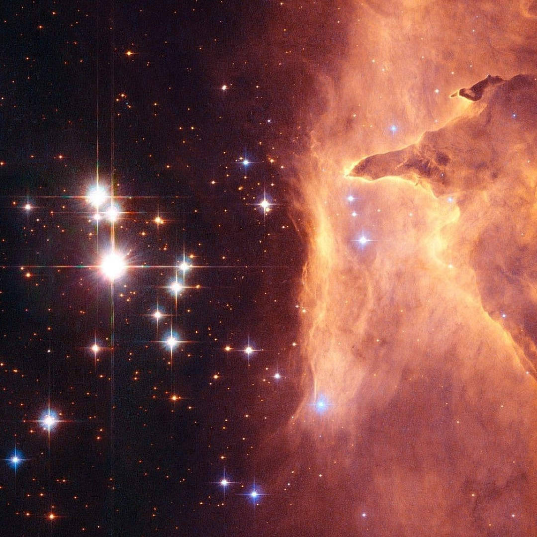 An image of outer space where bright, big stars dominated the left side of the image and are balanced out by a foggy nebula cloud on the right. Stars, poke through the nebula, although the cloud has dimmed their light.