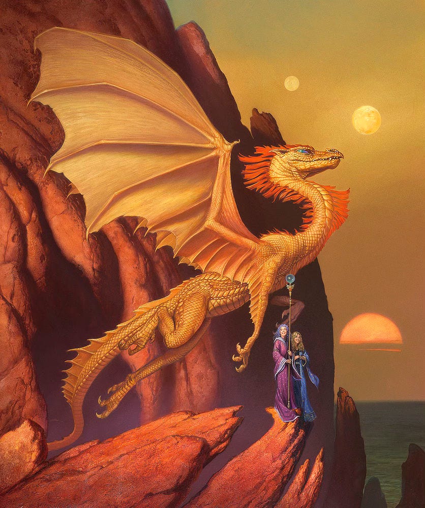 A golden dragon with orange tufts on its neck and head gracefully floats from a cliffside cave at sunset. The sun burns low crossed by clouds just above the horizon. Twin moons glow in the sky. A pair of women in sorceress gowns—one purple, one blue—stand on the rocks. One holds a tall staff topped with winged ornament and a blue orb atop it.