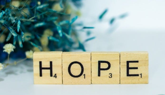 a wooden block that says hope next to a bouquet of flowers
