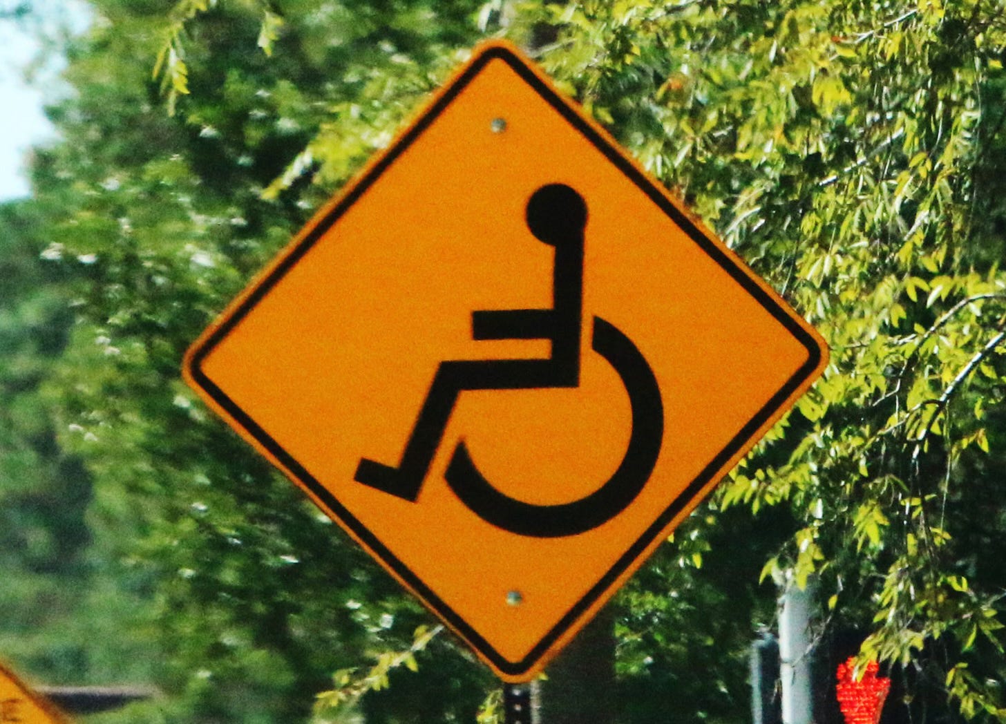 Orange diamond shaped traffic sign with wheelchair symbol