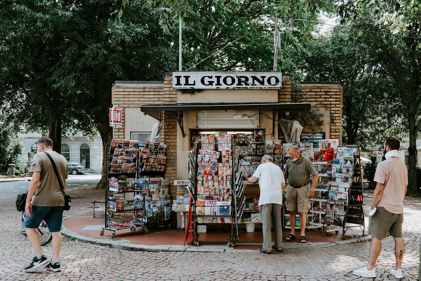 un gruppo di persone in piedi davanti a un chiosco di libri