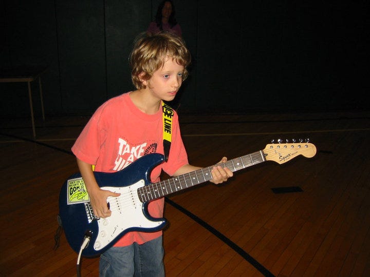 Henry at age 9 or so playing a Squier Stratocaster at a public park show.