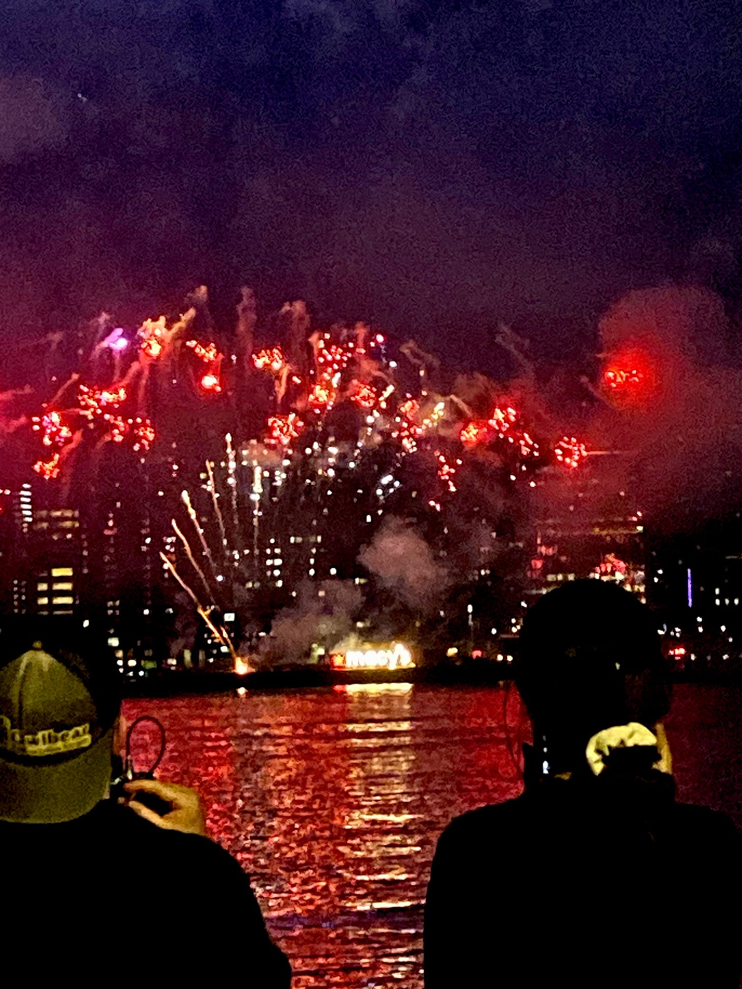 Fireworks over the East River and an illuminated Macy's barge.