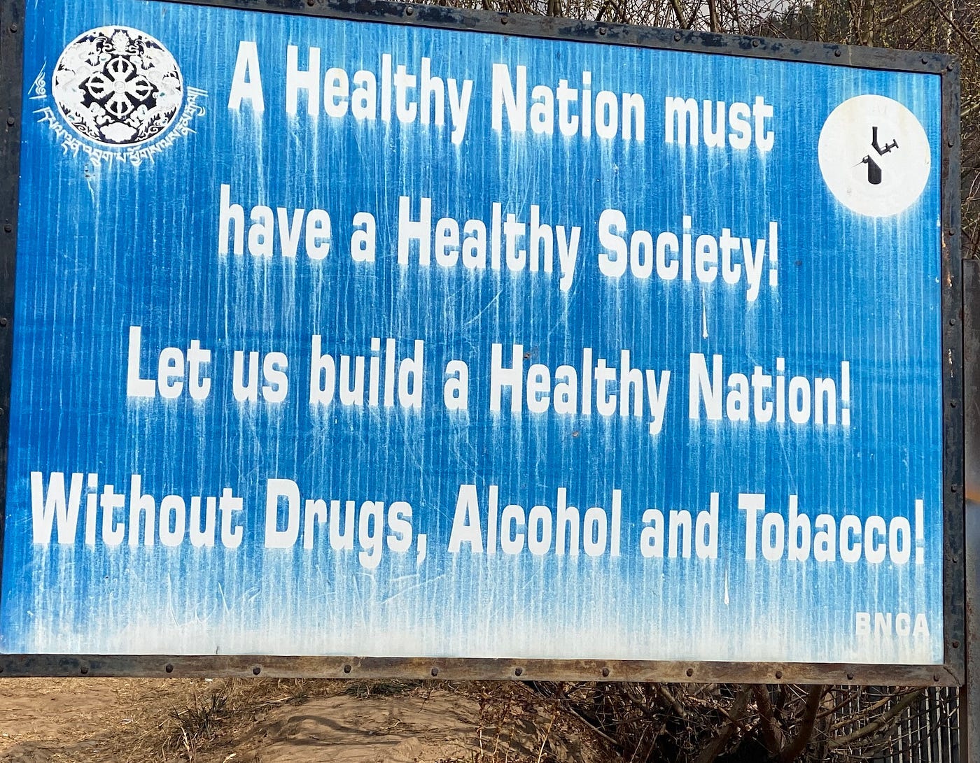 A roadside billboard. The text reads “A healthy nation must have a Healthy society! Let us build a Healthy Nation! Without Drugs, Alcohol and Tobacco!”