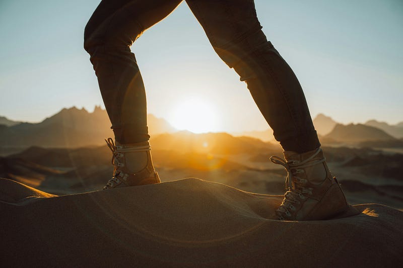 legs and feet of a person taking a step with sunlight shining through their legs
