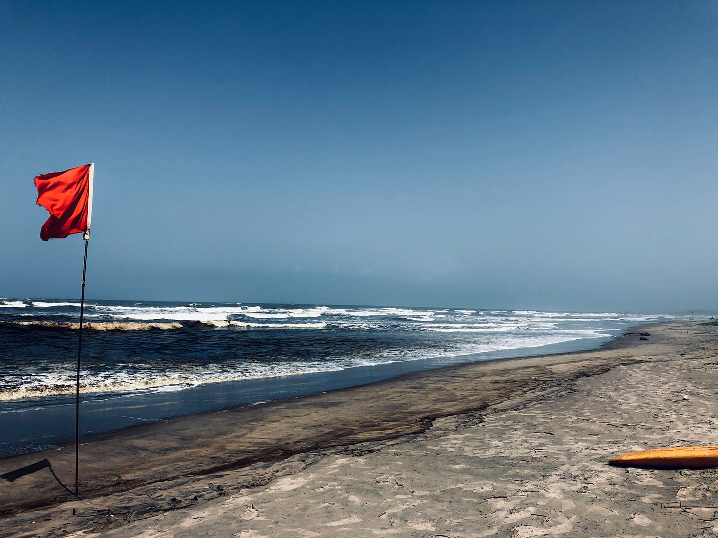 Red flag on a beach flying in the wind.