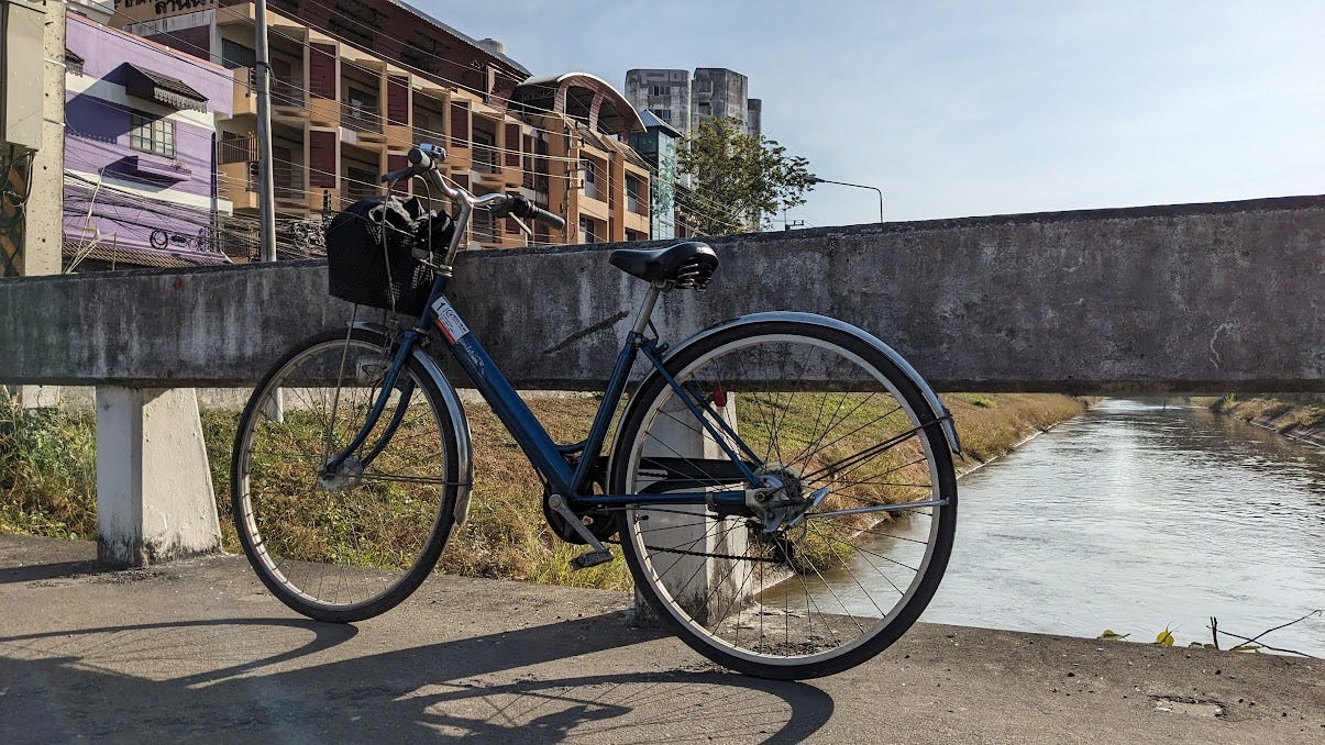 a bicycle leaning against a cement barrier on a sunny day in thailand
