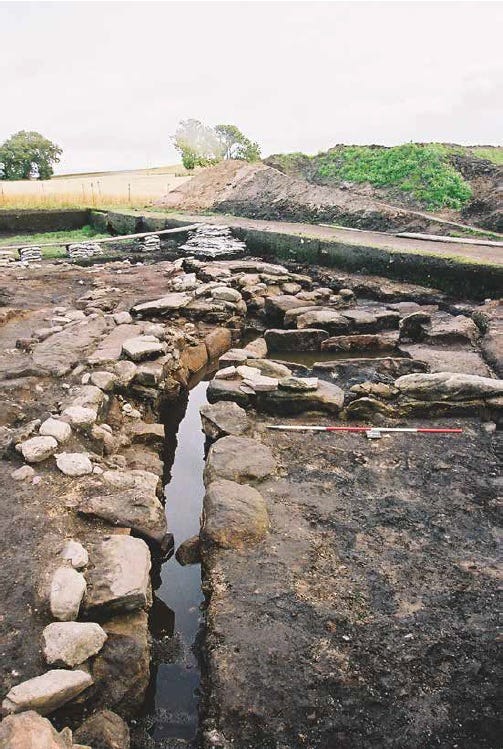 Photo of a stone culvert excavated at Portmahomack in Easter Ross. It's a stone lined drain running through an archaeological trench.
