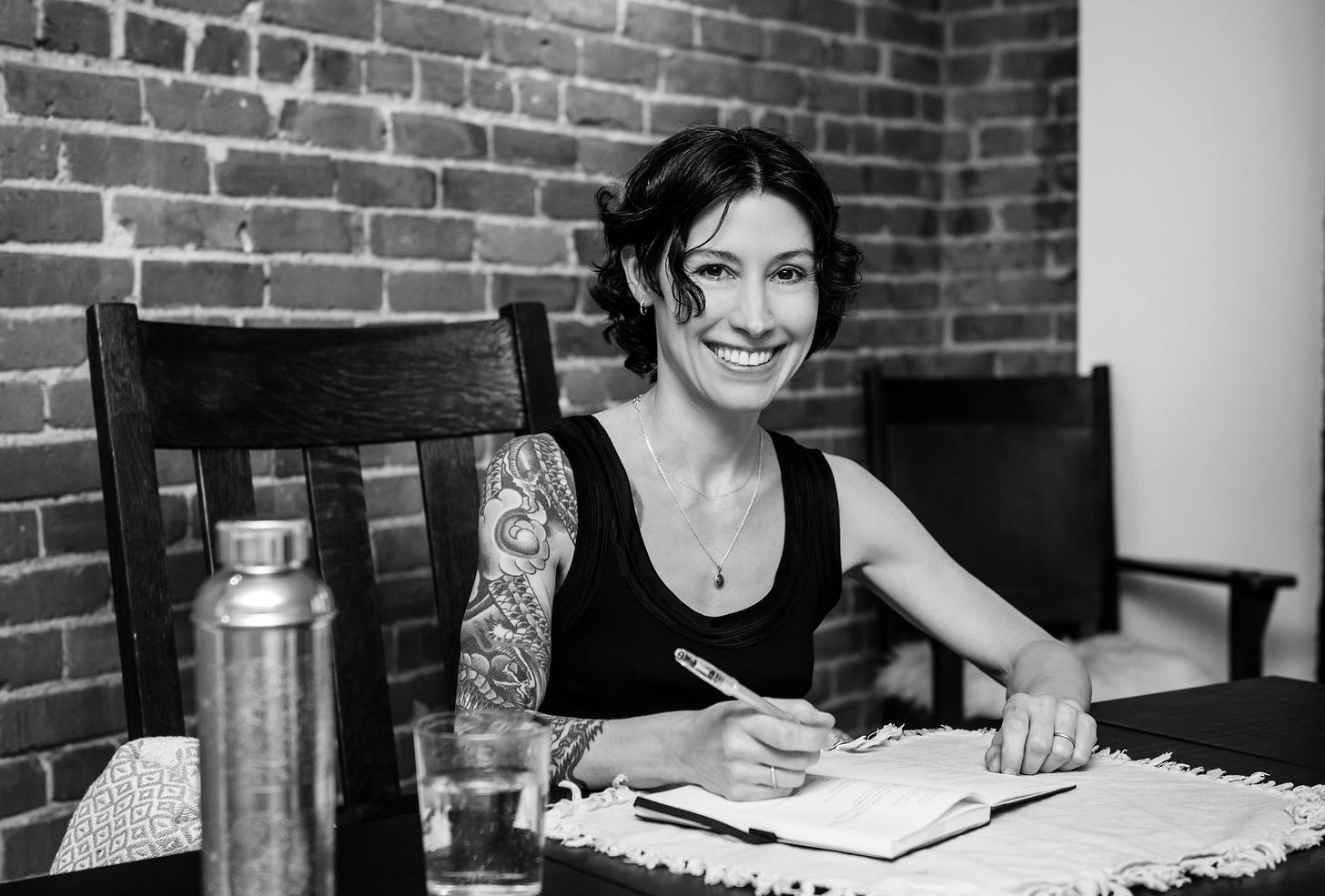 Black-and-white image of author writing in her journal at her desk