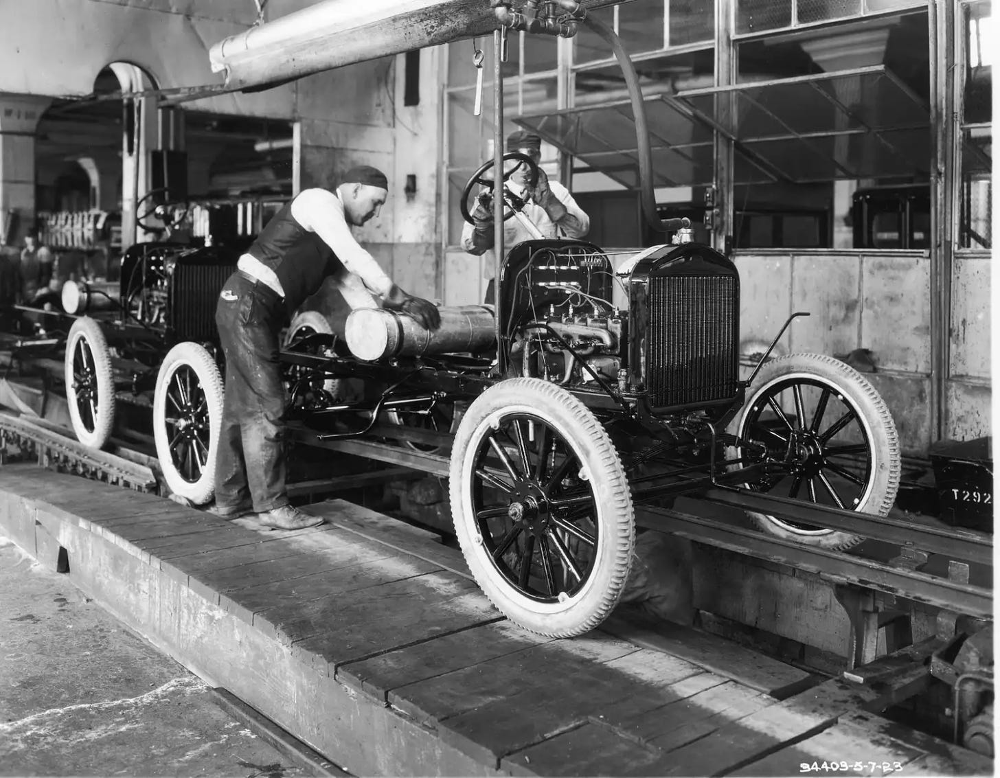 Picture of a worker attaching a gas tank on Ford&#39;s assembly line.