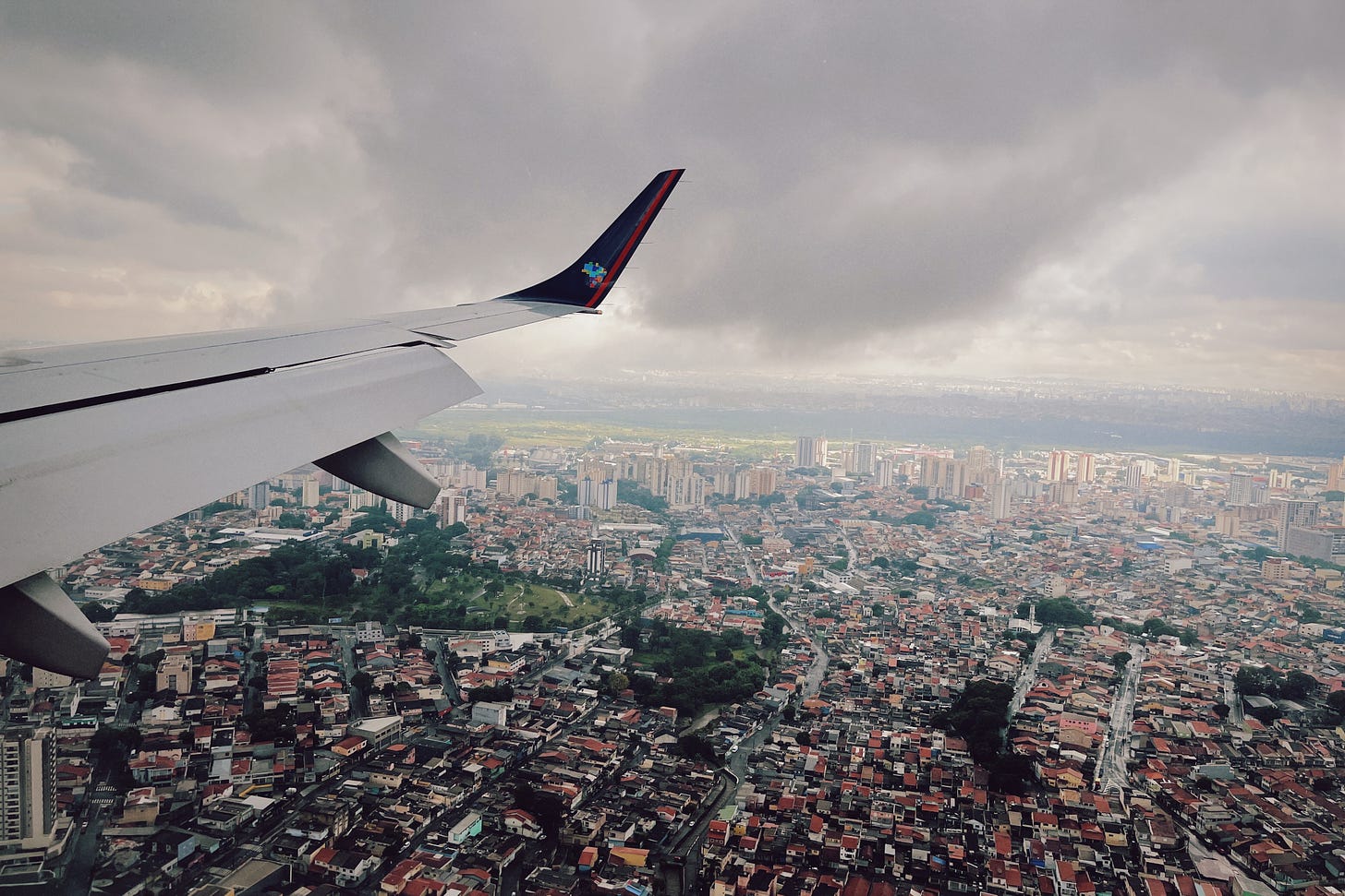 Photograph of São Paulo, seen from a plane. The wing of the plane is visible on the left side of the image.