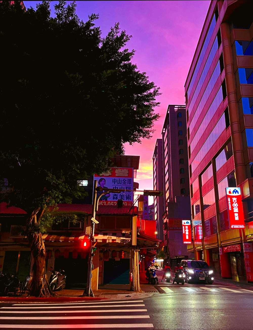 A bright pink and purple sunset seen behind the high rise buildings of Taipei's Zhongshan district