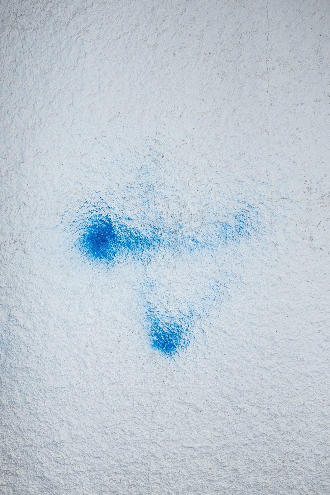 A textured white surface with blue spray paint.