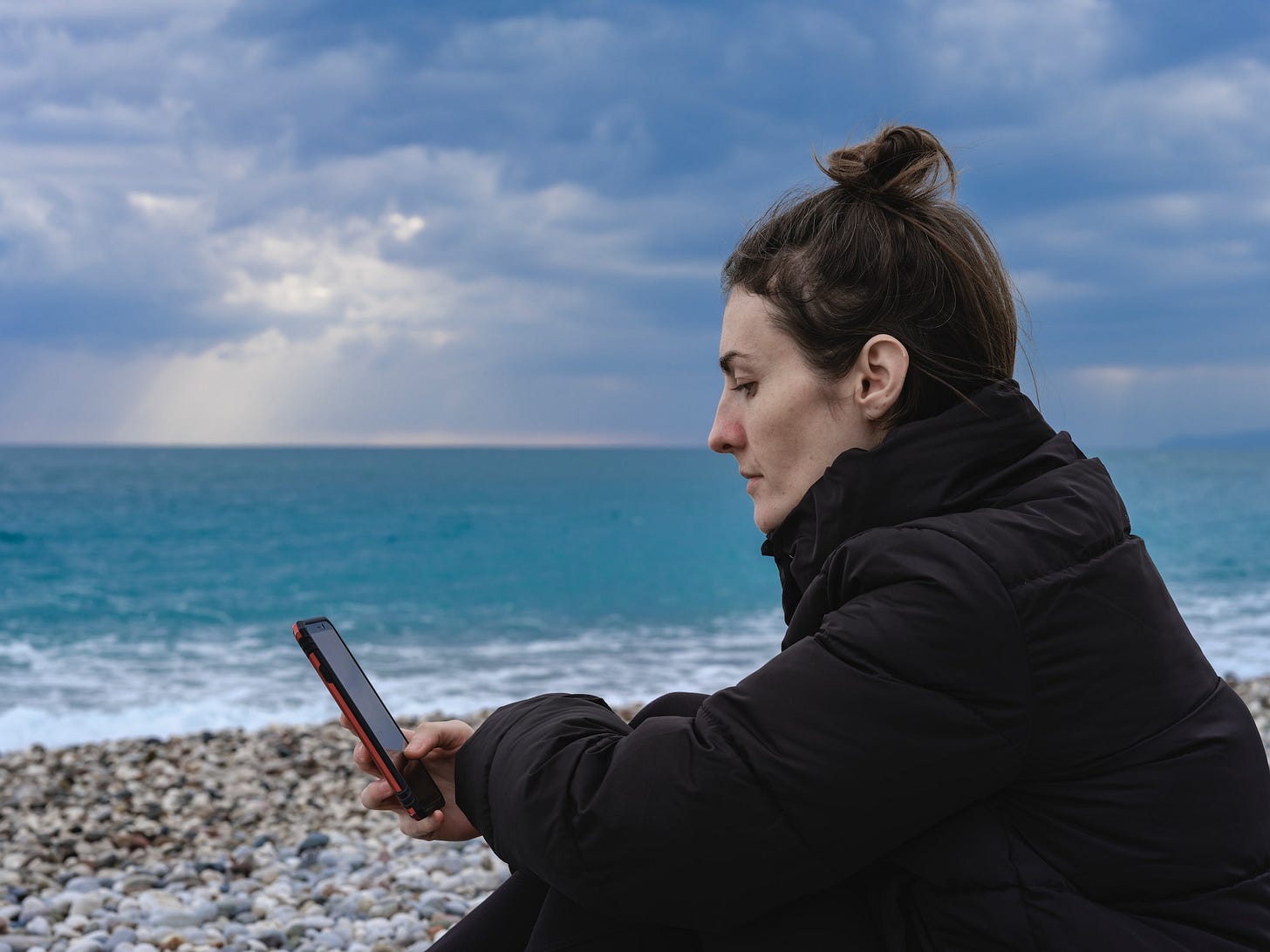 young woman looking at her phone on the beach