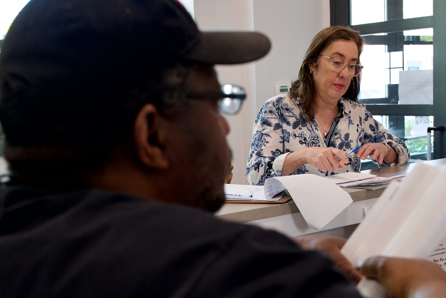 Laurel Peltier, an energy justice advocate who volunteers at the local nonprofit Cares, goes over utility bills to determine if her client Henry Burlock was overcharged by a private energy company. Credit: Aman Azhar/Inside Climate News