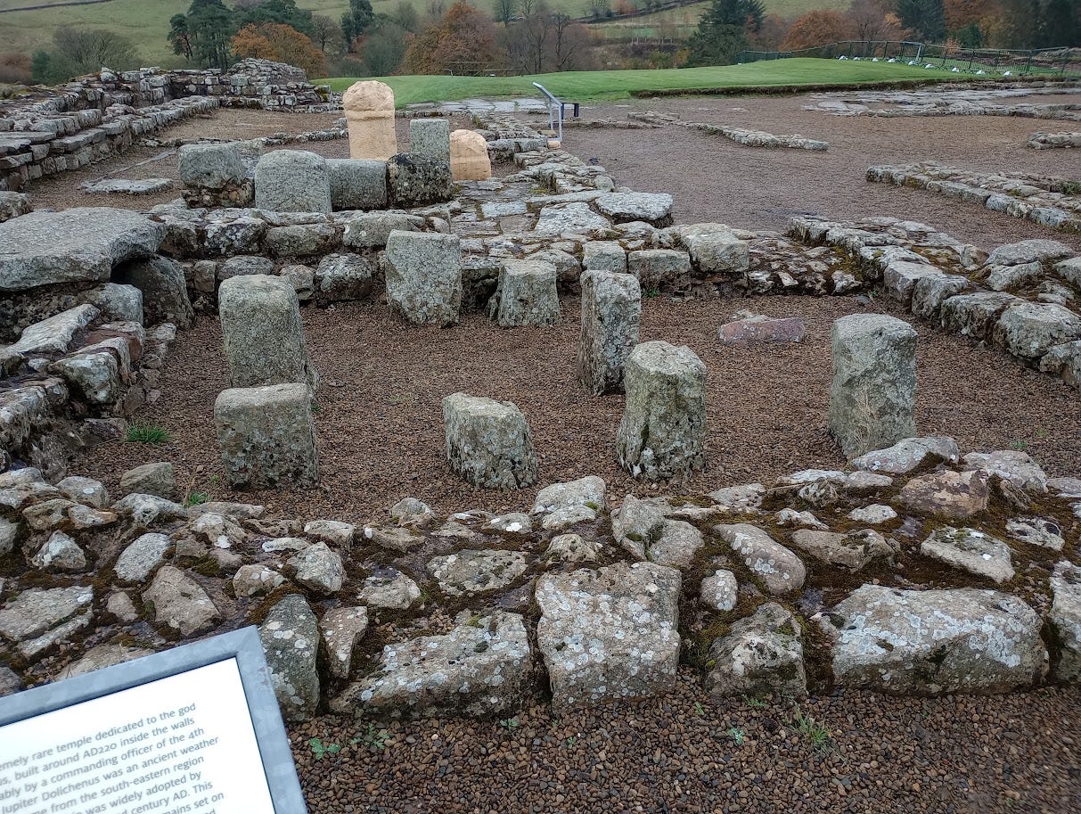 Stones in rough shape of two rooms, one with two narrow beige pillars, replicas of altars