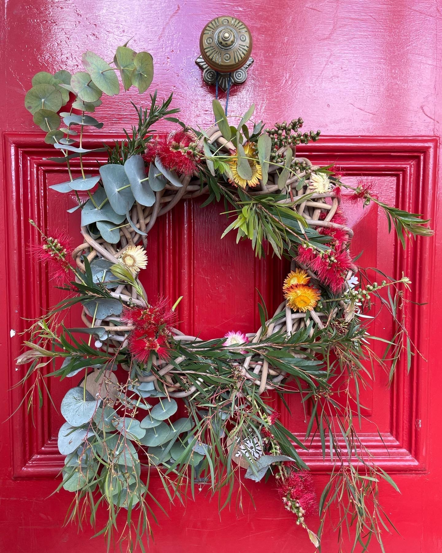 Red door with a handmade Christmas wreathe made of Australian native florals