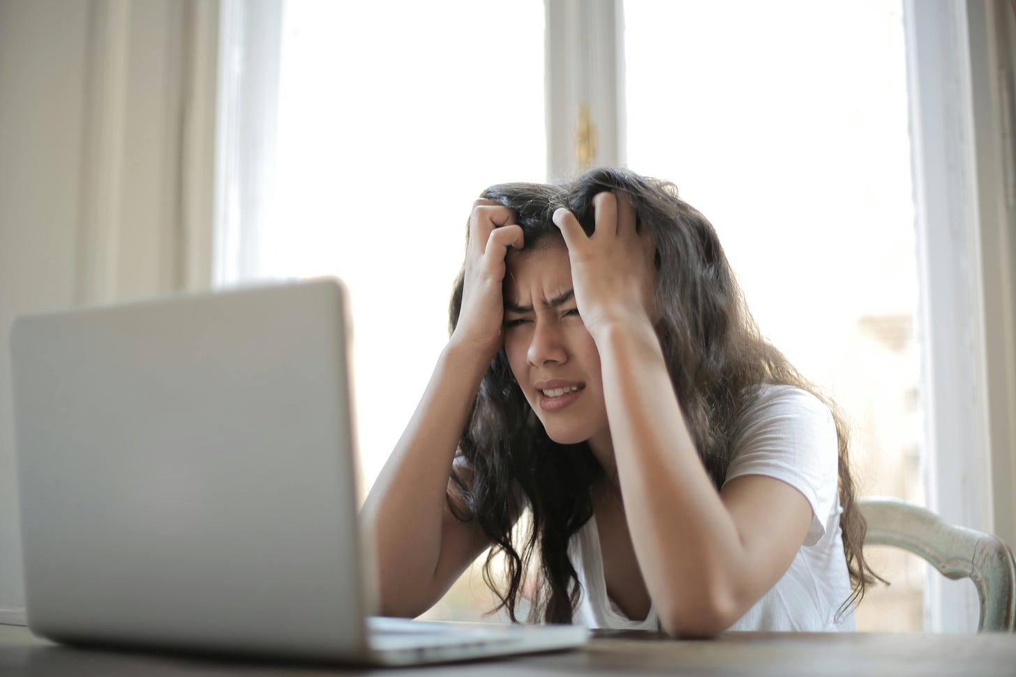 a frustrated Asian woman in front of a laptop.