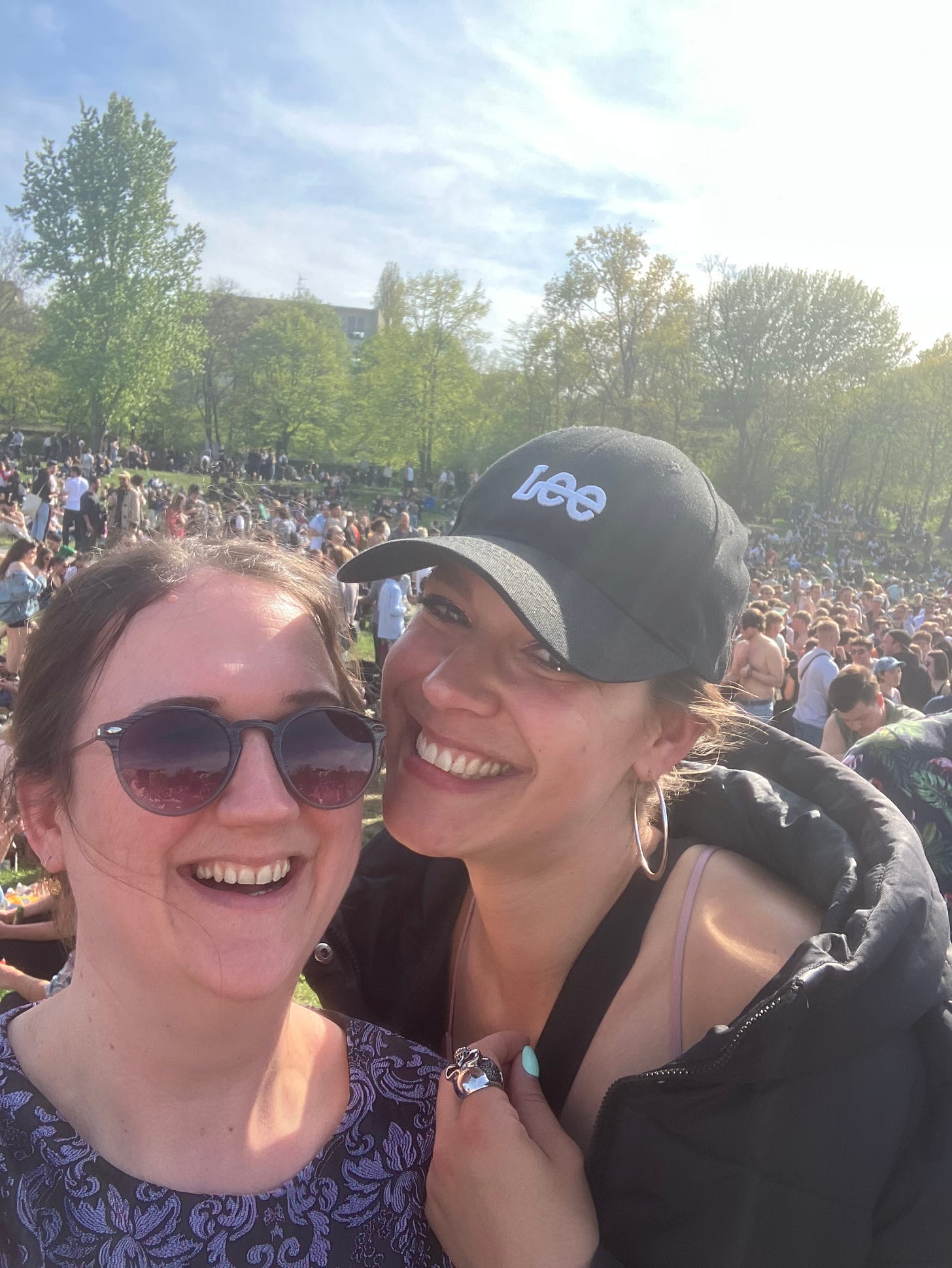 Me and my friend smiling in front of crowds in a park in Berlin on May Day
