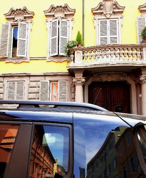 passeggiando a Modena, tanti dettagli architettonici e belle facciate colorate riflesse sui vetri di un'auto