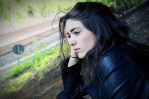 black haired young woman leaning on hands with face sad