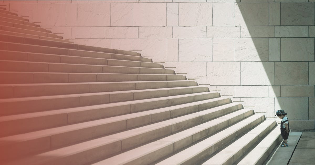 A small child stares at the first step of a large, intimidating staircase.