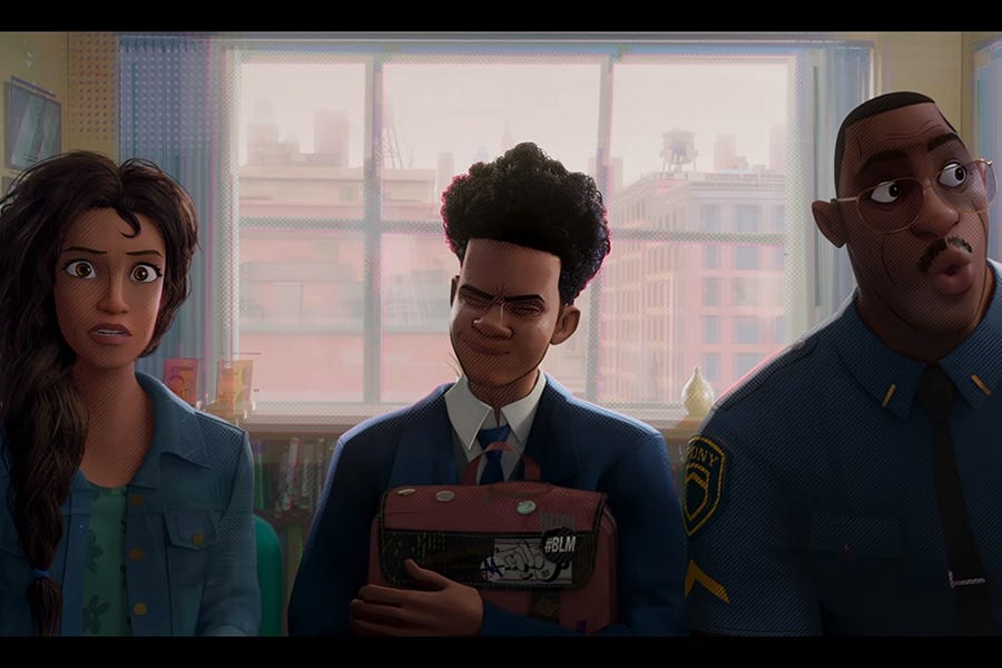 A screenshot from the film Spider-Man: Across the Spider-Verse, where protagonist Miles Morales sits between his mother Rio and his father Jefferson, a police sargent. On Miles's backpack are a graffiti'd "Hello My Name Is" sticker, and in its corner is a "#BLM" pin.