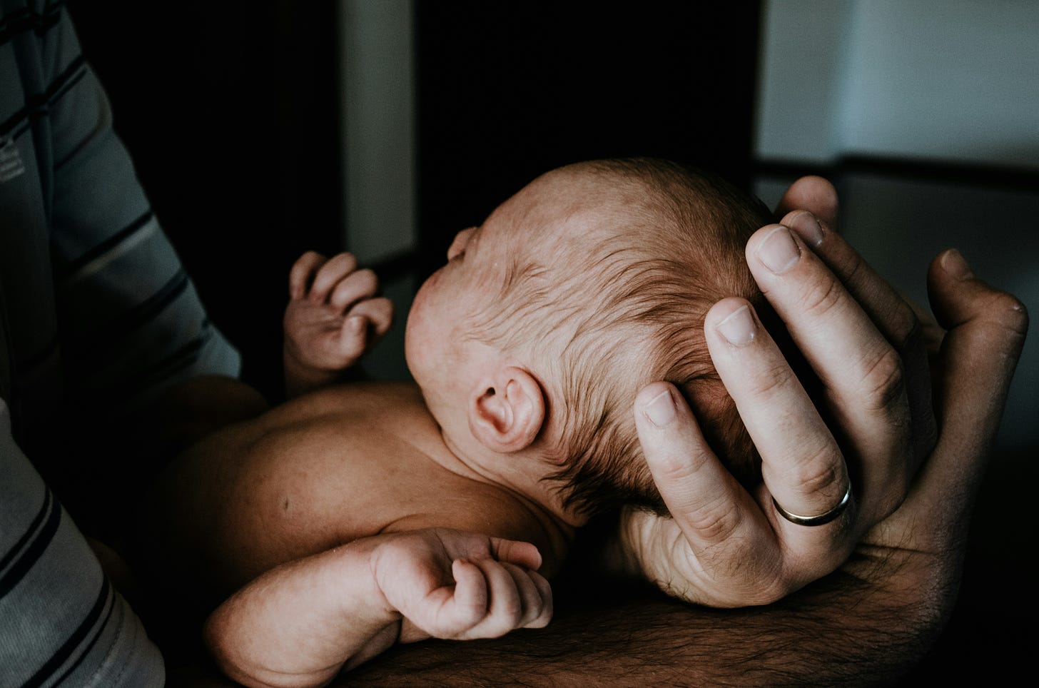 newborn baby being held in father's arms