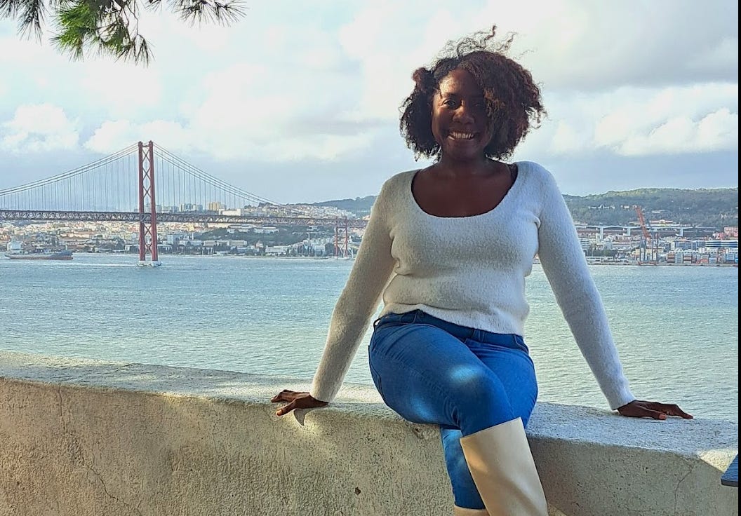 Black American woman Portugal expat Twanna Hines sitting at waterfront in Lisbon