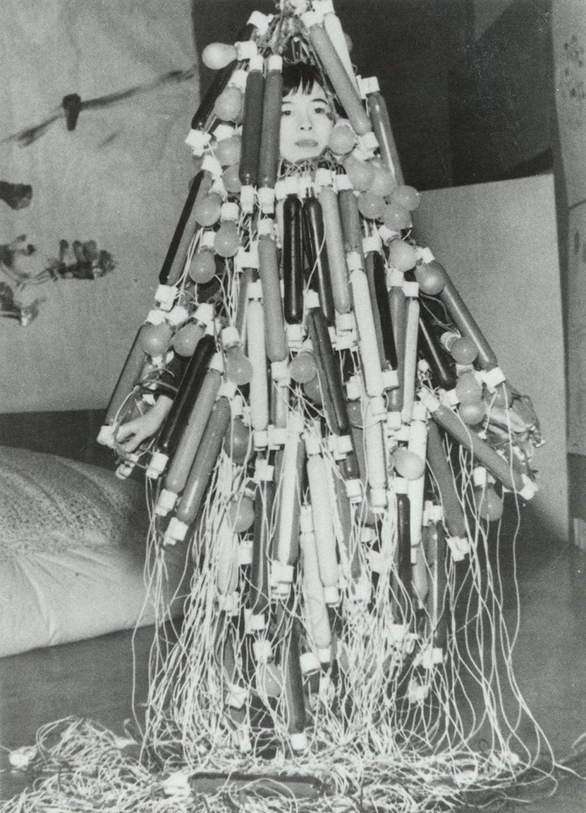 Woman enveloped from head to toe in dress made of long and short light bulbs