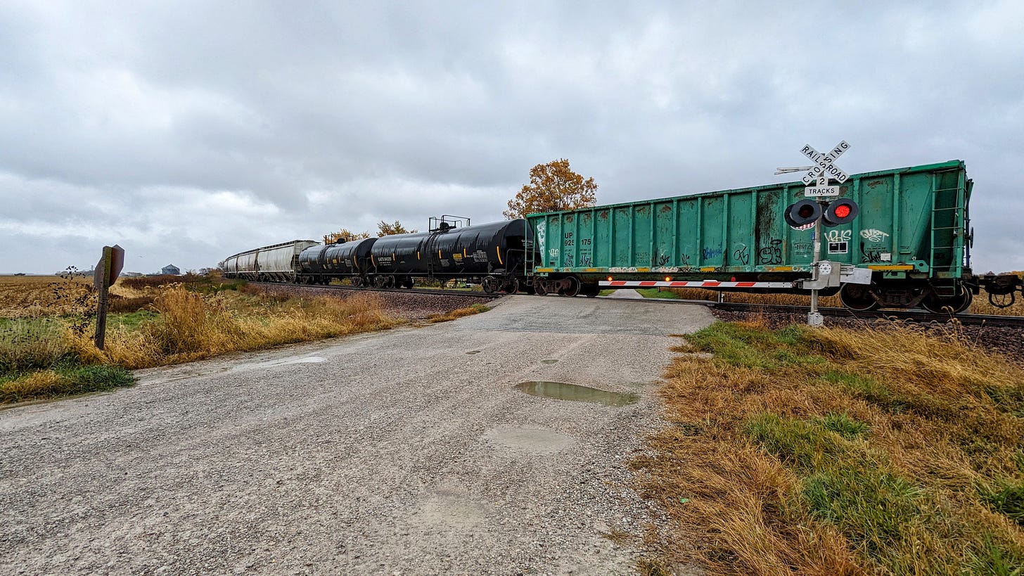 A train (mix of boxcars and tankers) stopped and blocking a railroad crossing