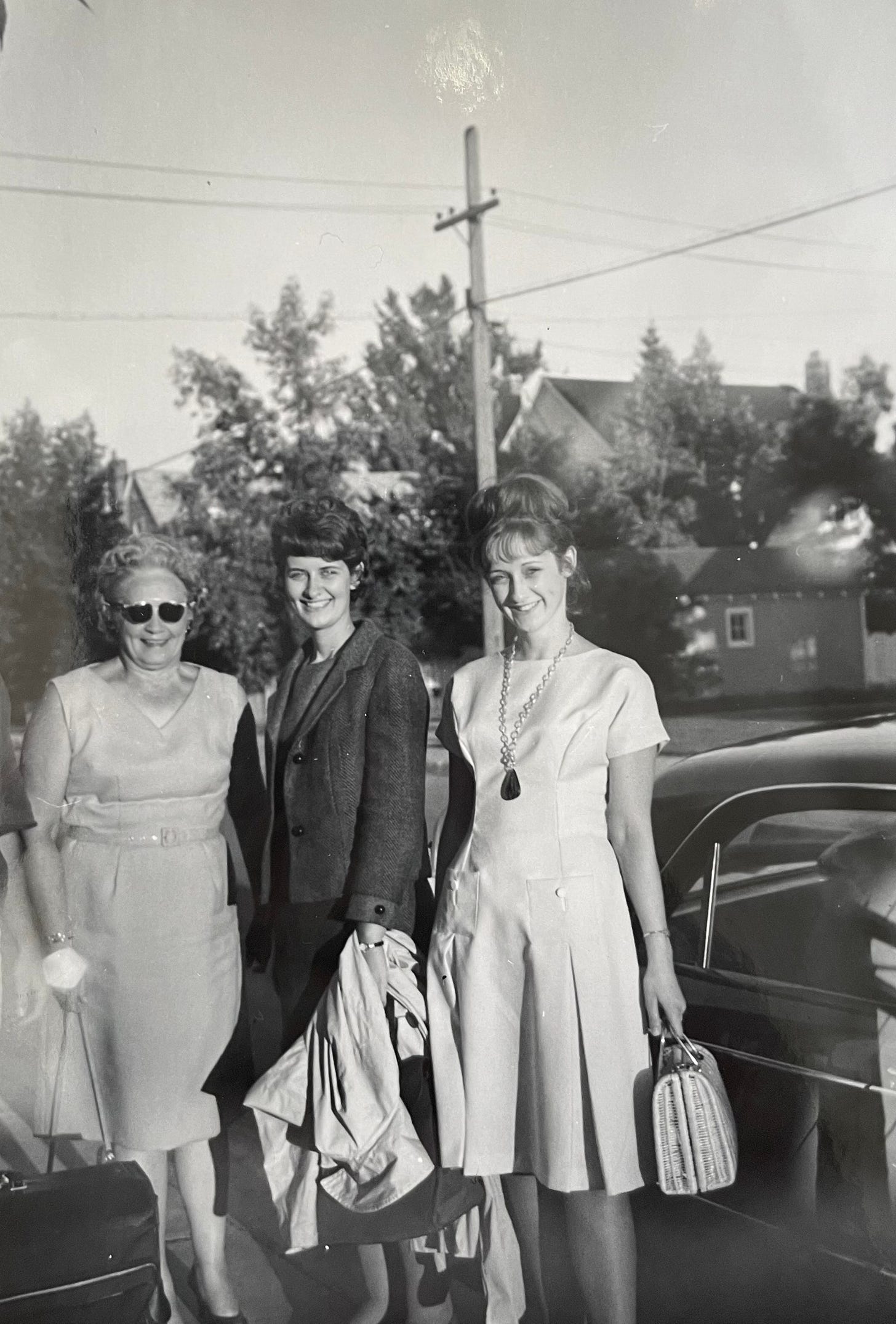 black-and-white photo of three women standing among houses and trees in 1963