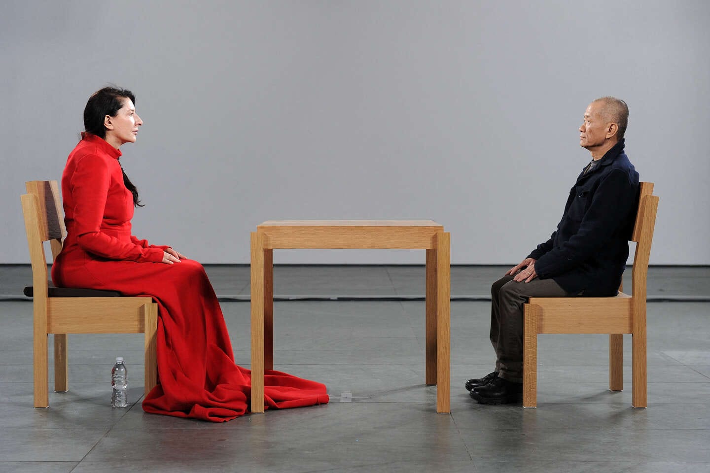 A woman in red sitting across from an Asian man dressed in brown