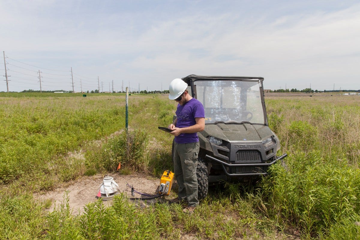 A scientist checks monitoring equipment in an open field at a carbon capture test site in Illinois.