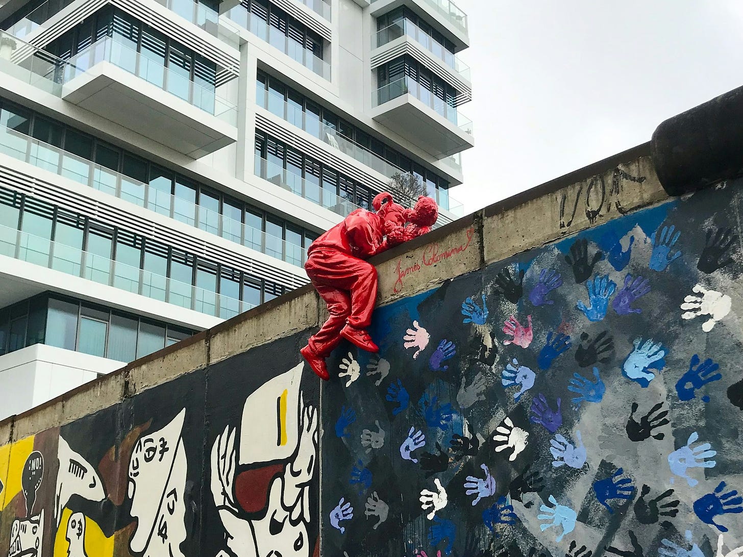 Un'installazione alla East Side Gallery di Berlino che raffigura una bambina, e il suo orsacchiotto, scavalcare il muro