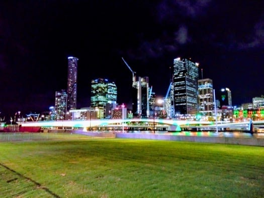 Lights of many colours on the riverfront, plus the skyscrapers behind are lit up