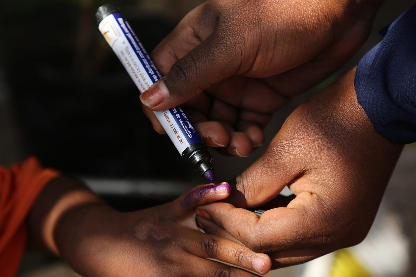 Health worker marking the finger of a child after vaccination