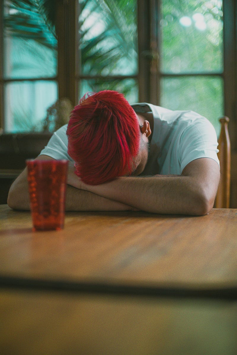 A person in depression, with head on folded hands resting on table