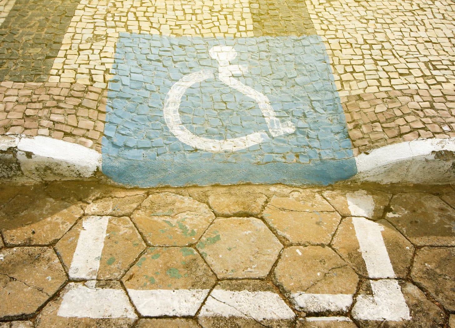 Wheelchair symbol painted onto a rough curb cut