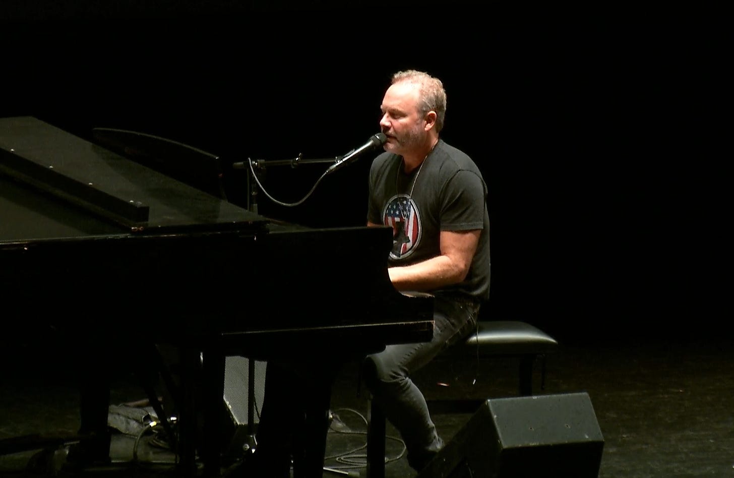 A person playing piano with microphone

Description automatically generated