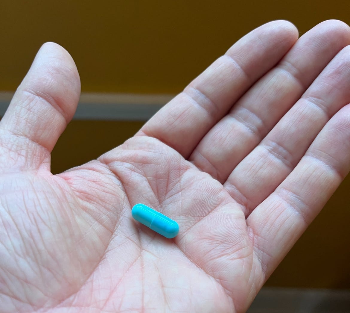 A capsule-style pill on the palm of my hands. It's a lovely turquoise. 