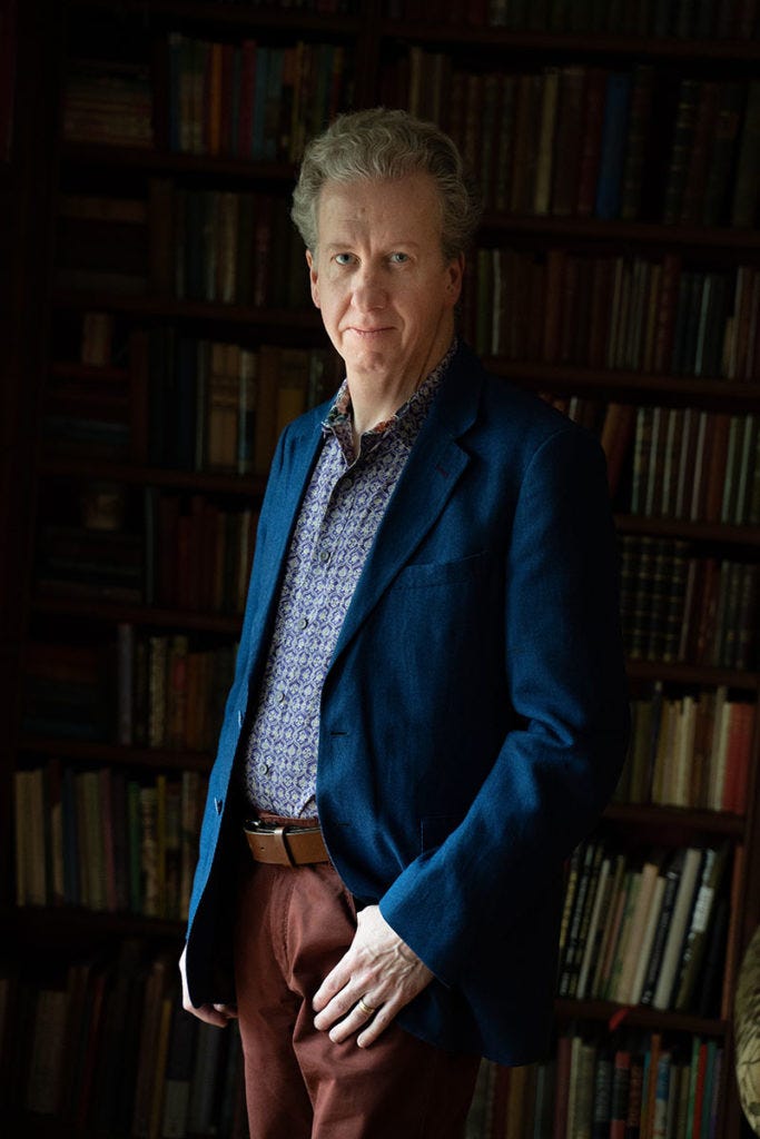 Caucasian man standing in front of bookshelf