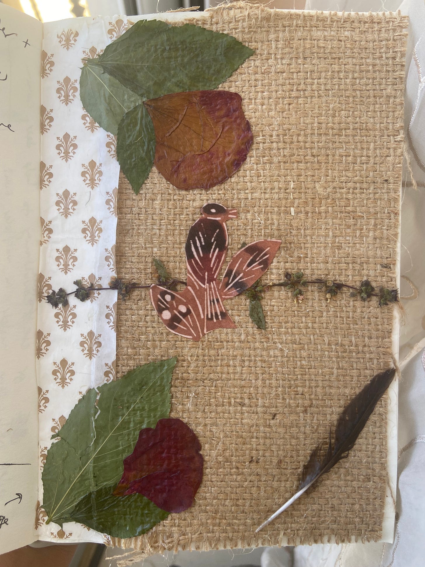 Photo of a collage art I have made with a cream burlap background and an image of a bird in the center. The left margin is decorated with white washi tape with gold florals and the top and bottom corners are decorated with molokhiya leaves and rose petals while the bottom right corner has a feather. The bird in the middle is perched on basil flowers. Photo of a collage art I have made with a cream burlap background and an image of a bird in the center. The left margin is decorated with white washi tape with gold florals and the top and bottom corners are decorated with molokhiya leaves and rose petals while the bottom right corner has a feather. The bird in the middle is perched on basil flowers.