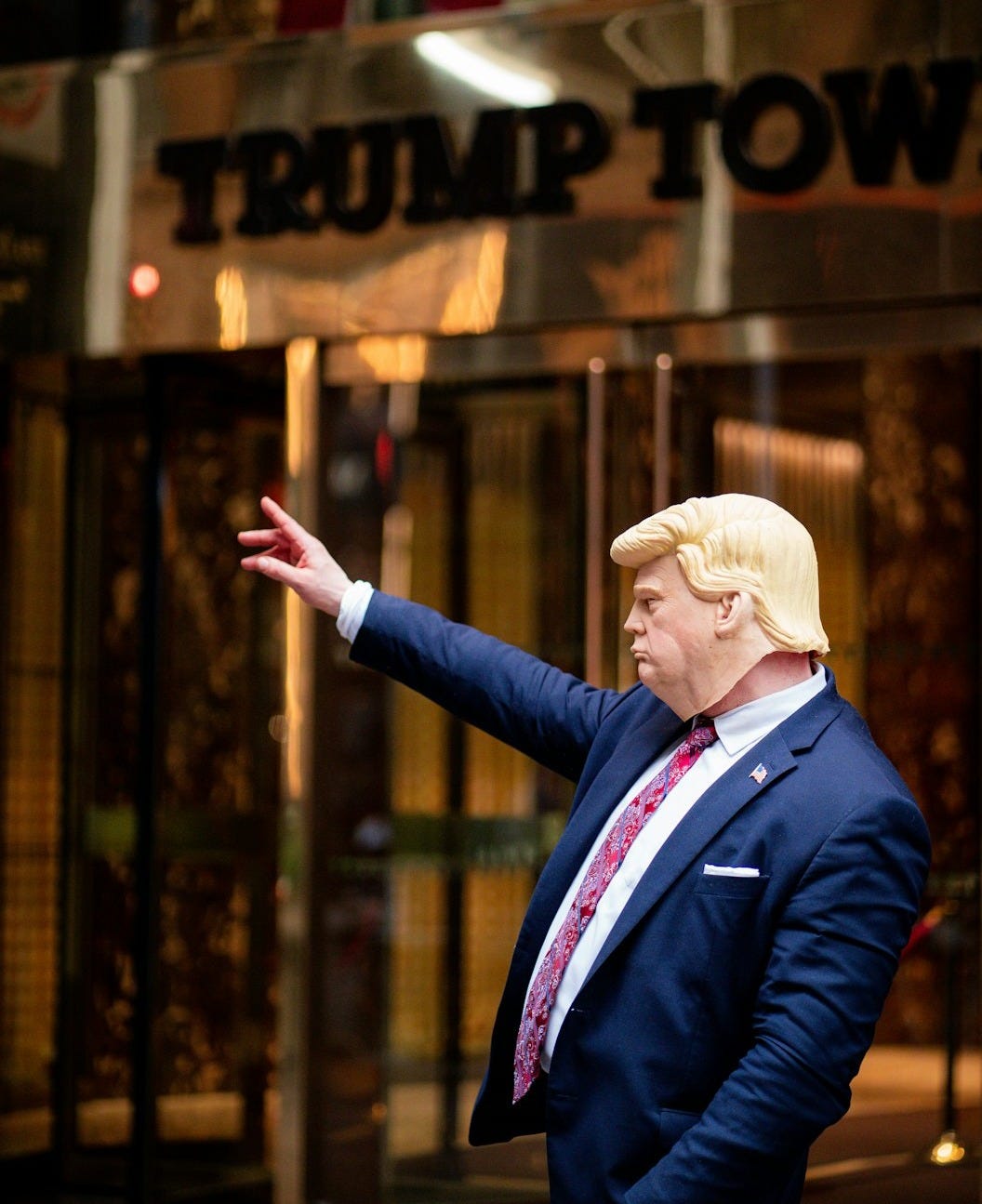 a man in a suit and tie standing in front of a trump building