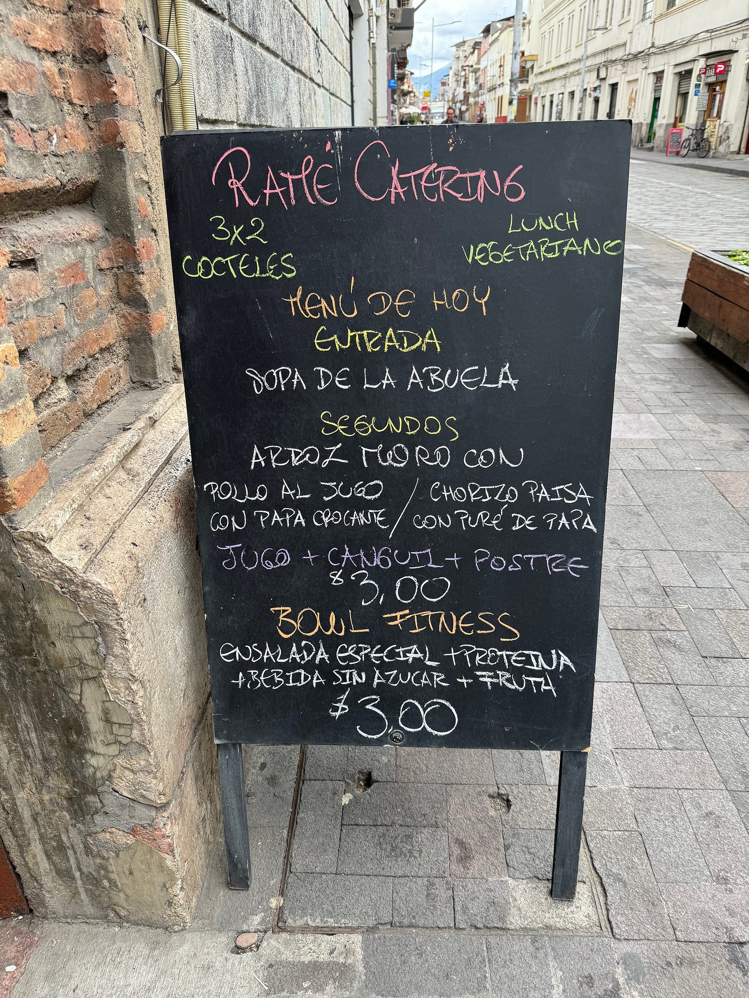 Pizarra en la calle ofreciendo un menú de primero, segundo y postre más bebida por $3 dólares.