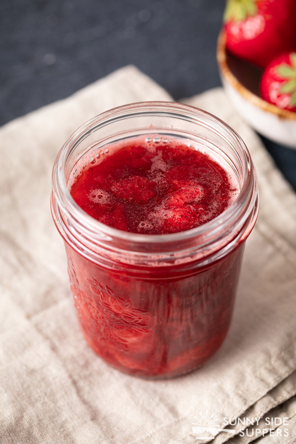 A mason jar filled with strawberry sauce.