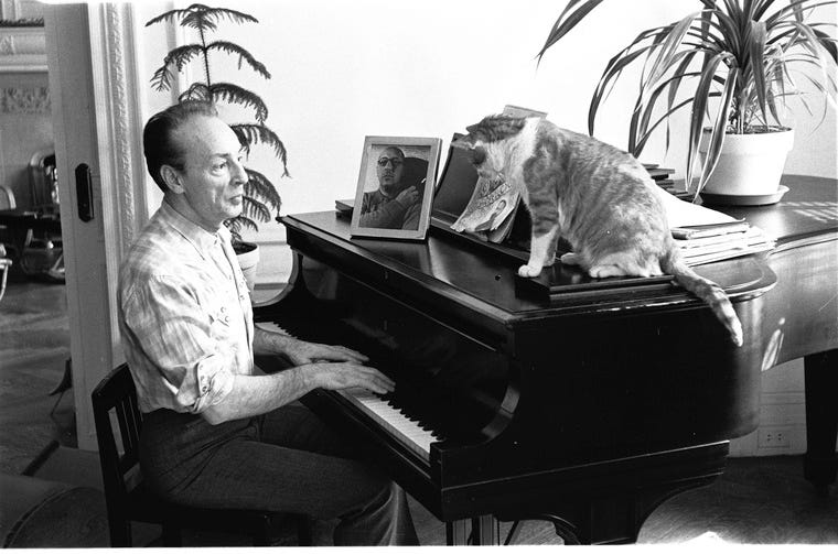 Balanchine sitting playing the piano at home with cat watching