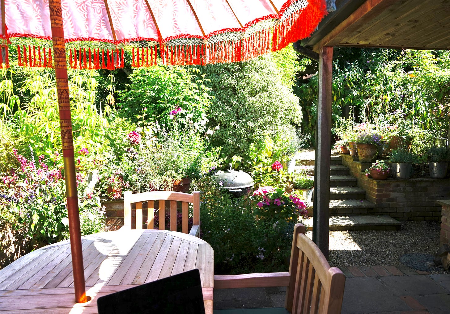 a garden table and chairs and umbrella in a garden