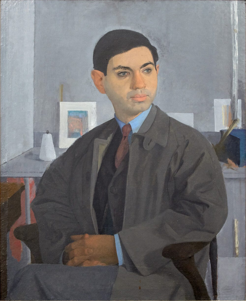 A young man seated with hands in his lap wearing an overcoat, suit, and tie. Objects are in the background on a table.